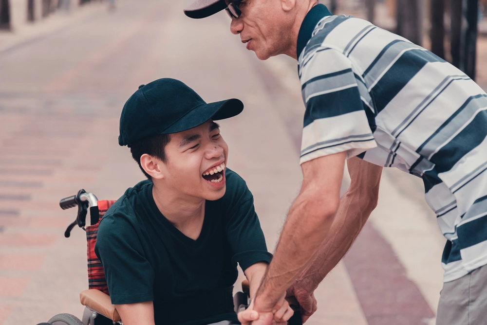 carer helping a young boy on wheel chair